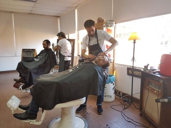 Barberos atendiendo a clientes en una barbería montada dentro de una oficina